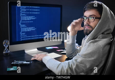 Man wearing hoodie hacking server in dark room Stock Photo