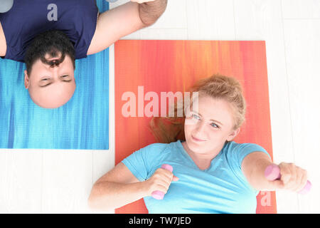Overweight couple doing exercises at home Stock Photo