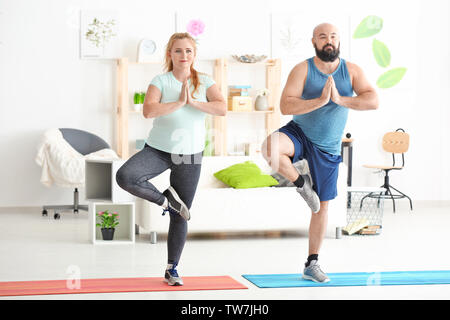 Overweight couple doing exercises at home Stock Photo