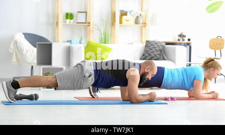 Overweight couple doing exercises at home Stock Photo