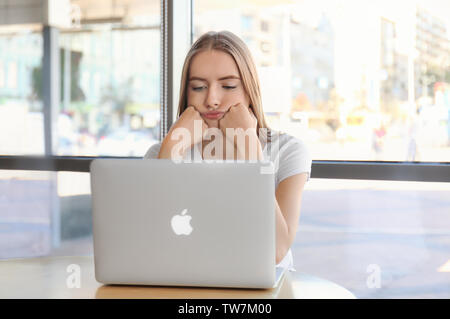 KIEV, UKRAINE - SEPTEMBER 28, 2017: Bored young woman using Apple Macbook Air indoors Stock Photo
