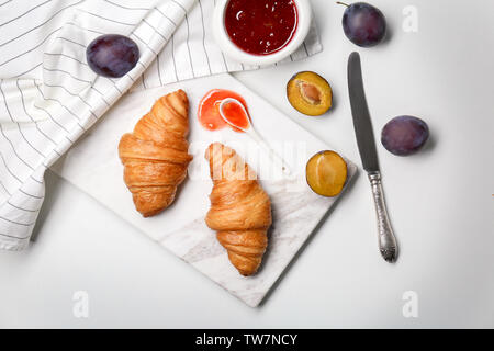 Composition with delicious croissants and plums on white background Stock Photo