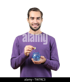 Casual man putting some coins into a piggy bank in living room Stock ...