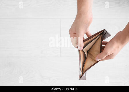 Hands of young man with empty purse on light background Stock Photo