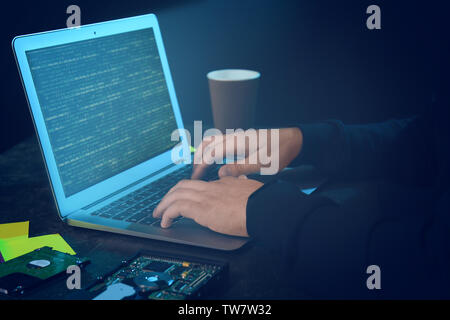 Hacker using laptop in dark room Stock Photo