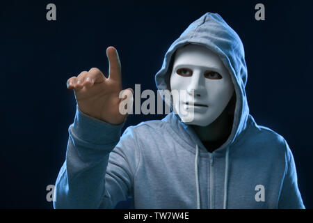 Hacker in mask on dark background Stock Photo