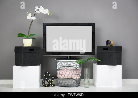 Modern TV on stand against grey wall background Stock Photo