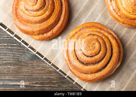 Cooling rack with sweet cinnamon rolls on table Stock Photo