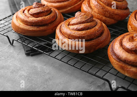 Cooling rack with sweet cinnamon rolls on table Stock Photo