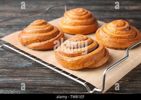 Cooling rack with sweet cinnamon rolls on table Stock Photo