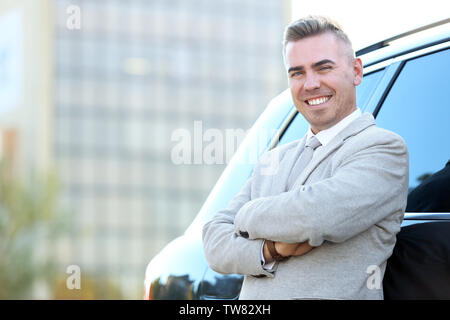 Man in formal wear standing near car on city street Stock Photo