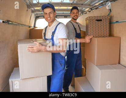 Delivery men unloading moving boxes from car Stock Photo