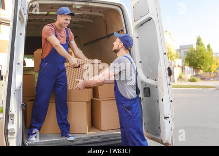 Delivery men unloading moving boxes from car Stock Photo