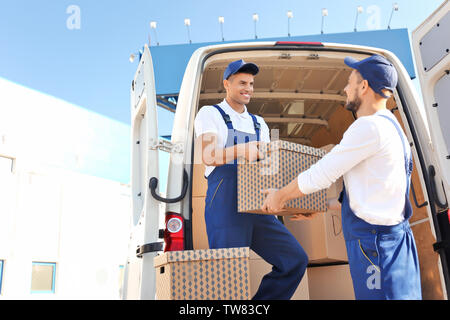 Delivery men unloading moving boxes from car Stock Photo