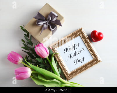 Gift box, pink tulips and photo frame with words 'Happy Mother's day' on light wooden background Stock Photo