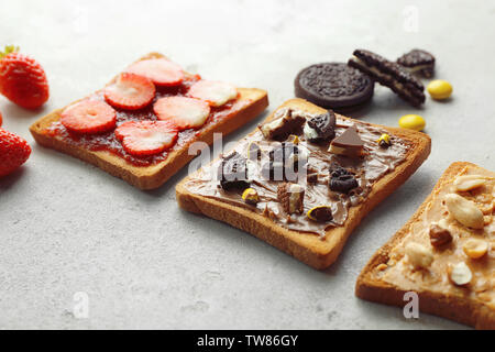 Delicious toasts with peanut butter, chocolate paste and strawberries on grey background Stock Photo