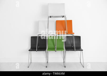 Construction made of chairs on white wall background Stock Photo