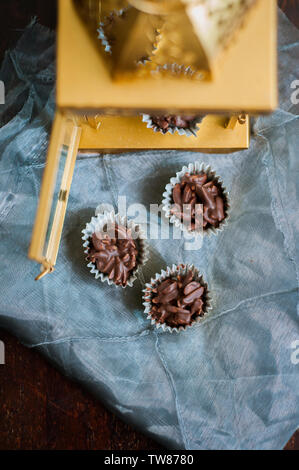 Chocolate Covered Almonds in golden paper cups with golden lighthouse in the background. Stock Photo