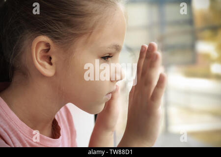 Little sad girl near window. Abuse of children concept Stock Photo