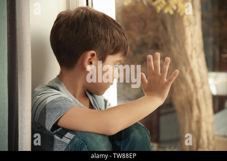 Little sad boy near window. Abuse of children concept Stock Photo