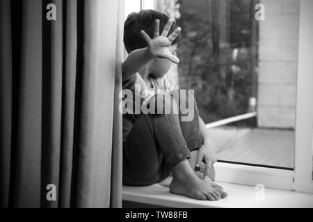 Helpless little boy near window. Abuse of children concept Stock Photo