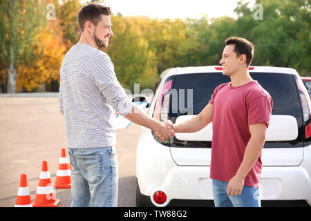 Instructor and young man passed driving license exam Stock Photo