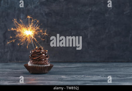 Tasty chocolate cupcake with sparkler on wooden table Stock Photo