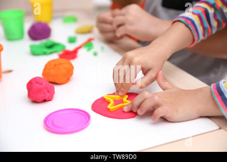 Little children engaged in playdough modeling at daycare, closeup Stock Photo