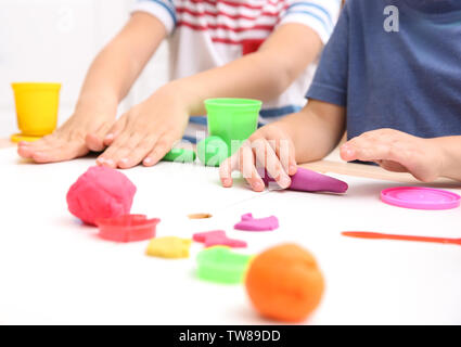 Little children engaged in playdough modeling at daycare, closeup Stock Photo