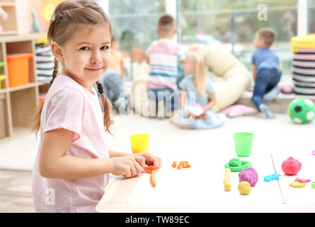 Little girl engaged in playdough modeling at daycare Stock Photo