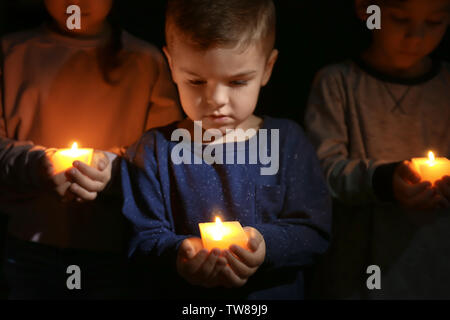 Little children holding burning candles in darkness Stock Photo