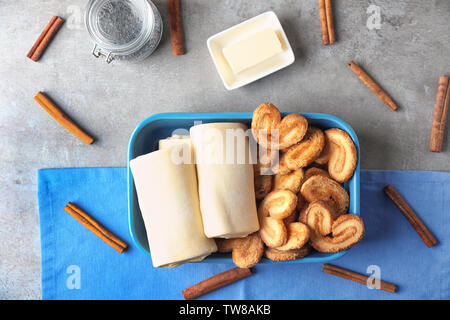 Baking dish with raw flaky dough and cookies on table, top view Stock Photo