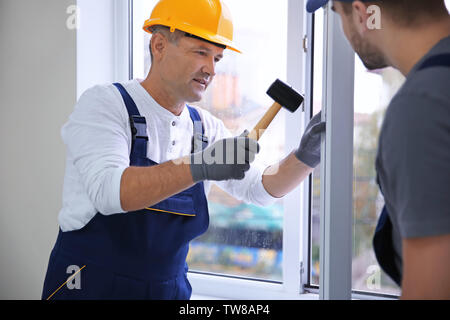 Construction worker with trainee installing window in house Stock Photo