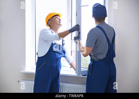 Construction worker with trainee installing window in house Stock Photo