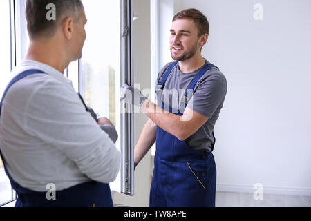 Construction worker with trainee installing window in house Stock Photo
