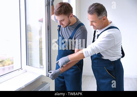 Construction worker with trainee installing window in house Stock Photo