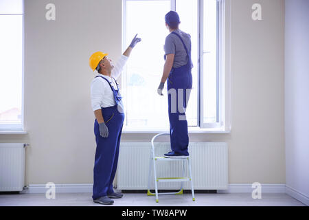 Construction worker with trainee installing window in house Stock Photo