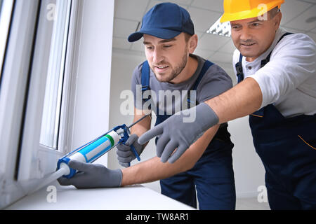 Construction worker with trainee installing window in house Stock Photo
