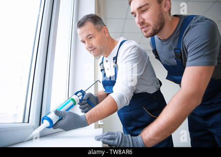 Construction worker with trainee installing window in house Stock Photo