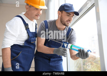 Construction worker with trainee installing window in house Stock Photo