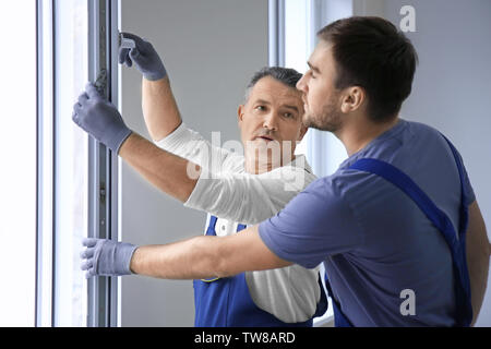 Construction worker with trainee installing window in house Stock Photo