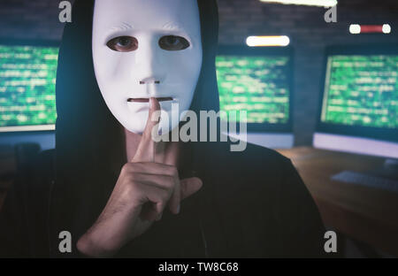 Masked hacker in dark room with computers. Threat of cyber attack Stock Photo
