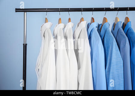 Clean shirts hanging on rack in laundry Stock Photo