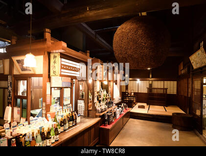 Sake brewery shop interior at old town of Takayama city with Sugidama, brown cedar ball, hanging inside. Takayama, Gifu prefecture, Japan Stock Photo