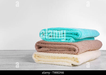Stack of fresh towels on wooden table against white background Stock Photo