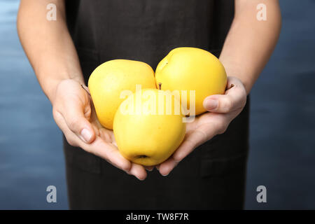 Woman holding ripe yellow apples on color background Stock Photo