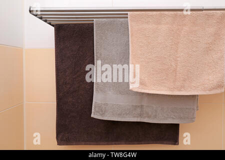 Soft towels drying on rack in bathroom Stock Photo