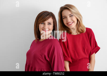 Attractive young woman with her mother in matching dresses on white background Stock Photo