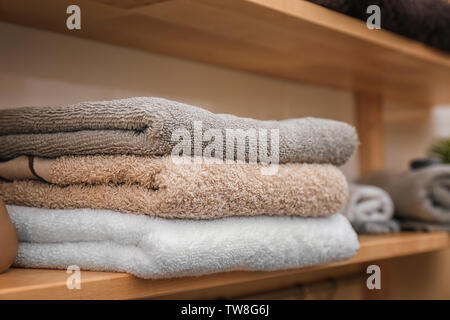 Soft towels on wooden shelf indoors, closeup Stock Photo