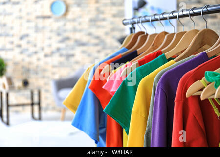 Rack with rainbow clothes indoors Stock Photo - Alamy